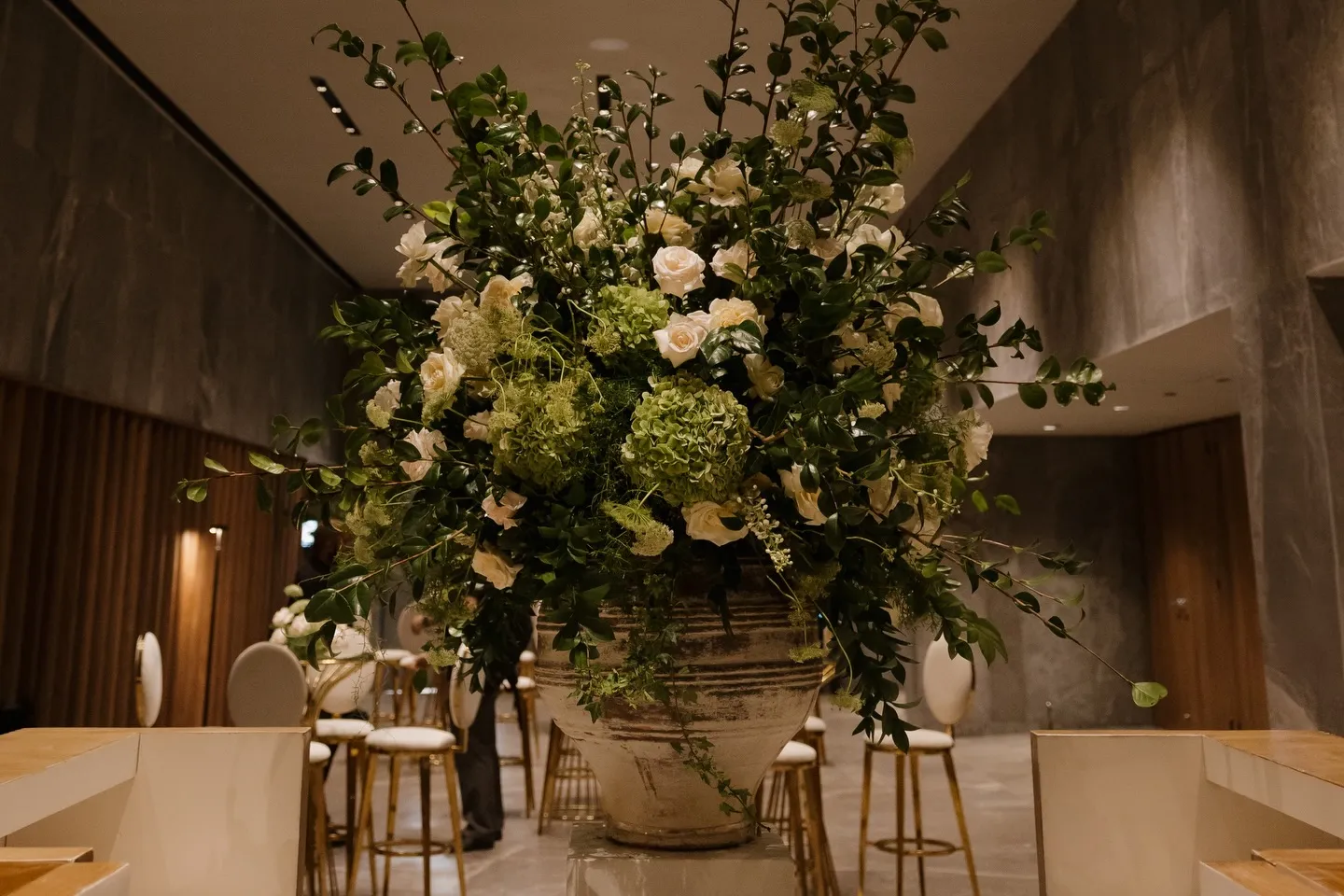 Arreglo floral monumental de follaje y rosa blanca junto a la barra