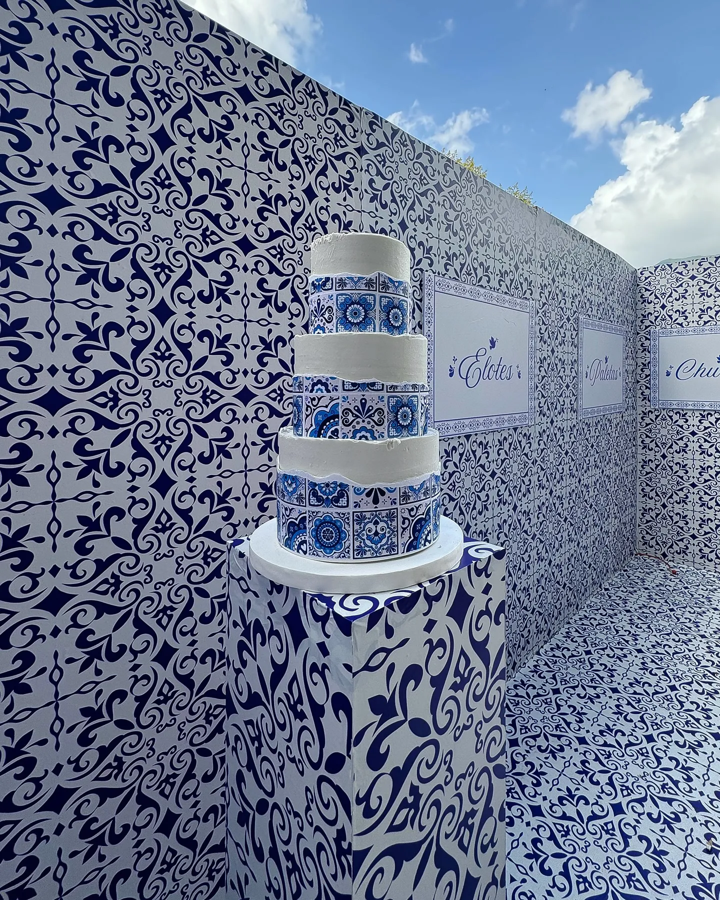 Pastel de tres pisos decorado en talavera azul frente al muro de patrón