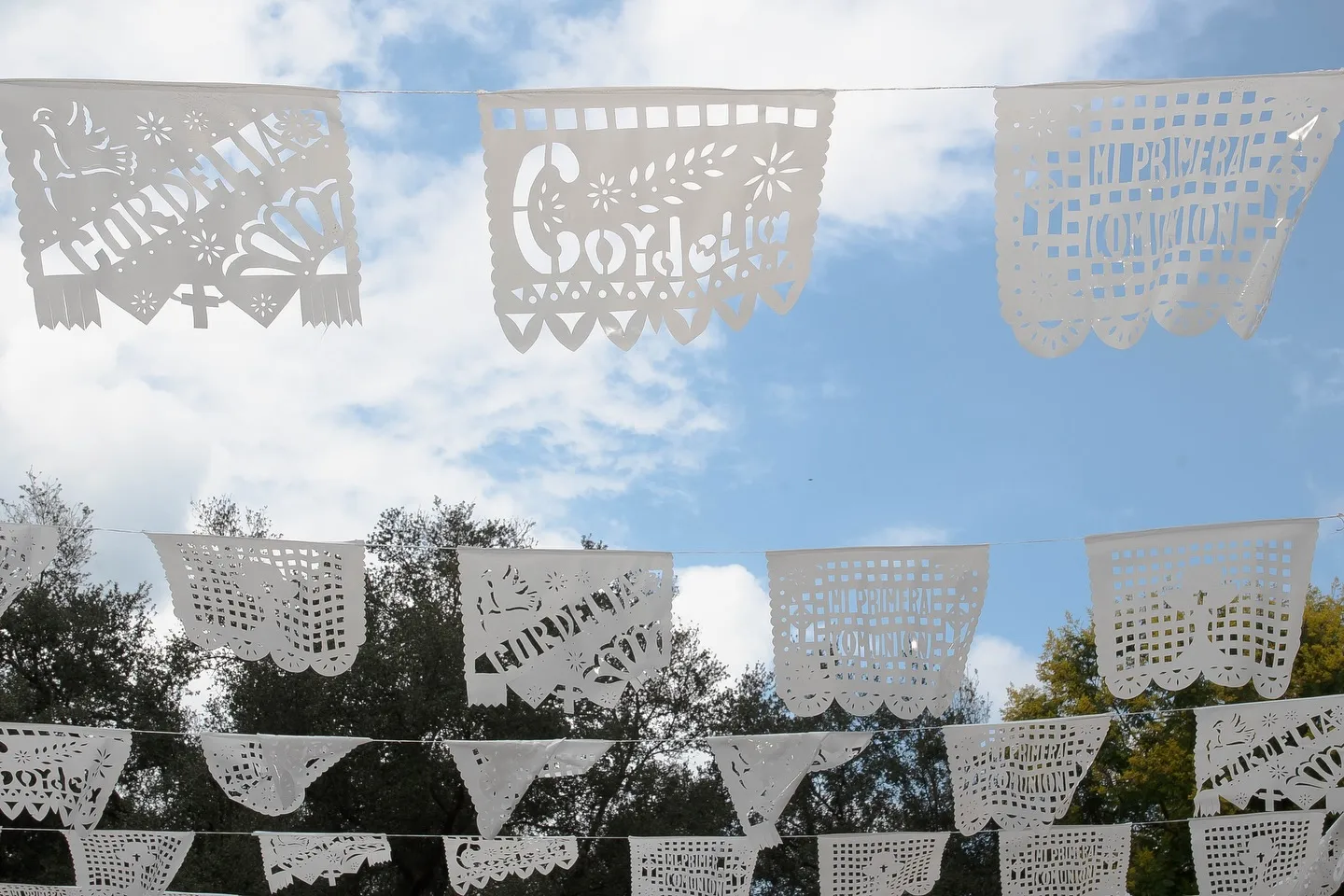 Papel picado blanco tendido entre los árboles contra el cielo