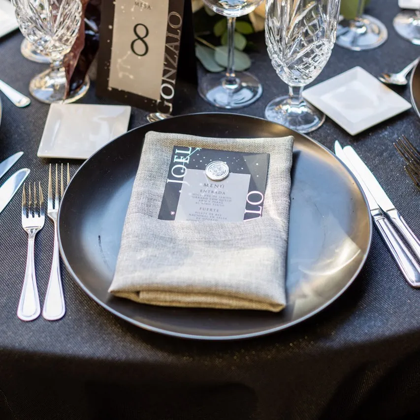 Detalle de servicio de mesa con plato de peltre, menú impreso y cristal cortado