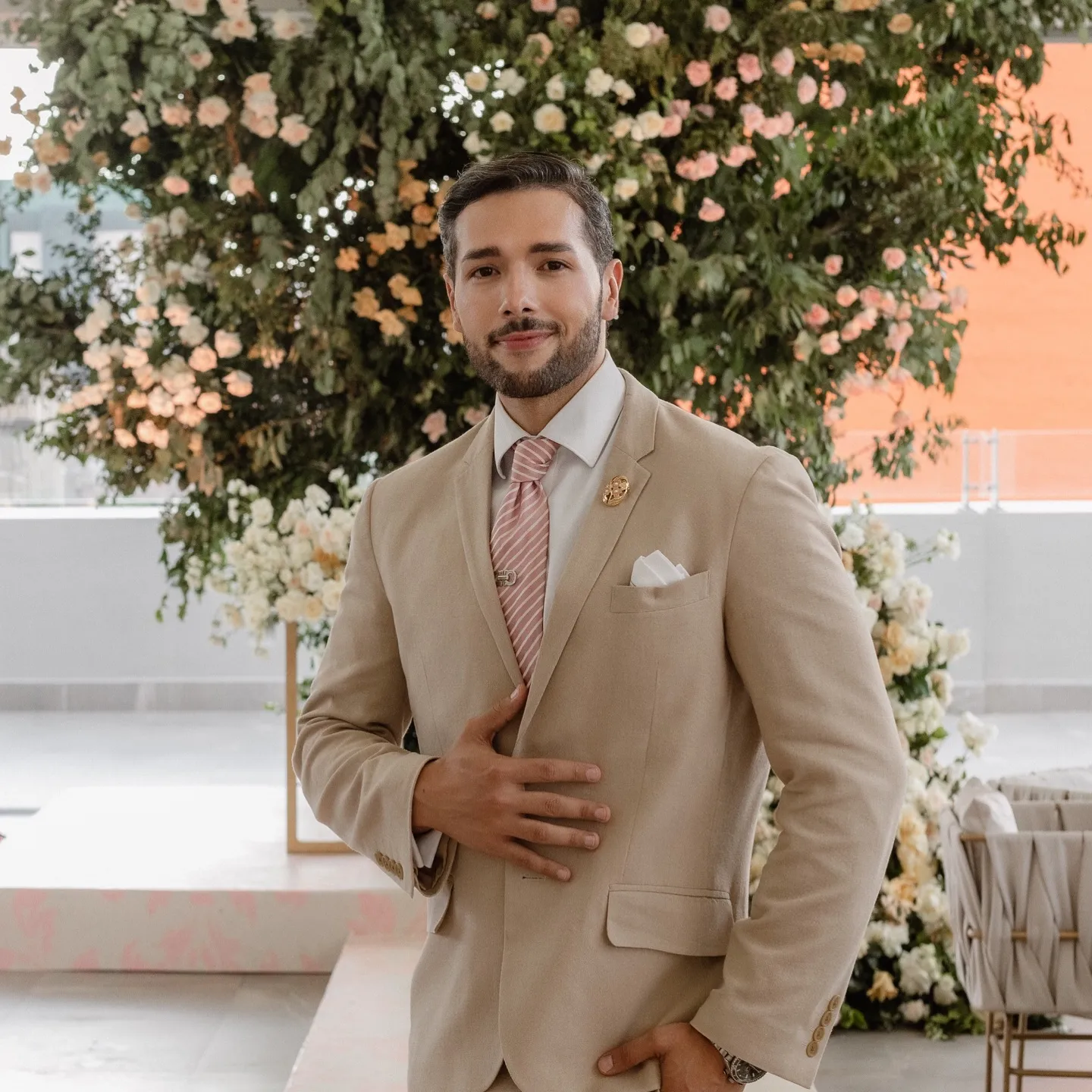 Antonio Olmos de traje beige frente a una instalación floral en terraza