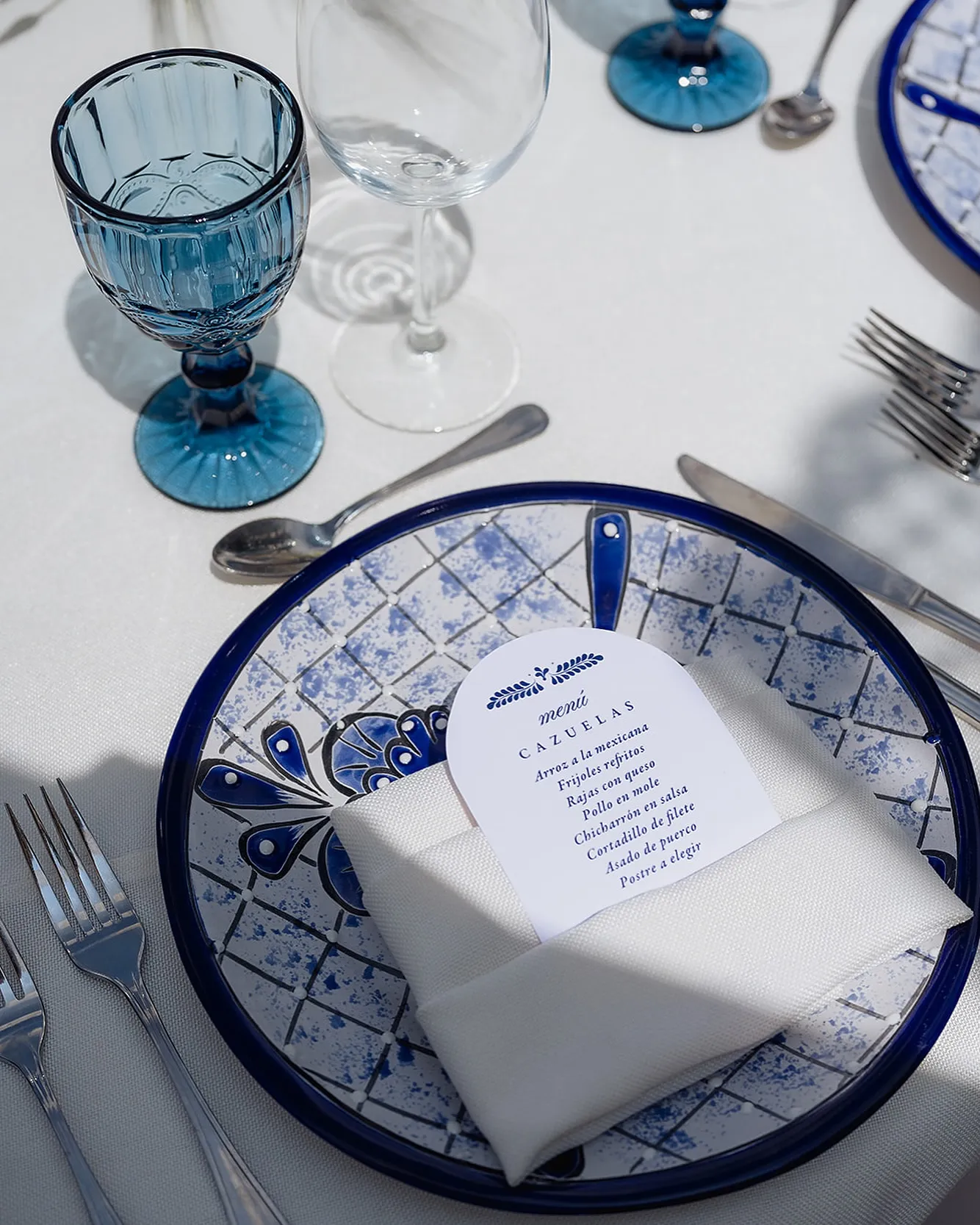 Detalle de plato de talavera con menú impreso y servilleta blanca