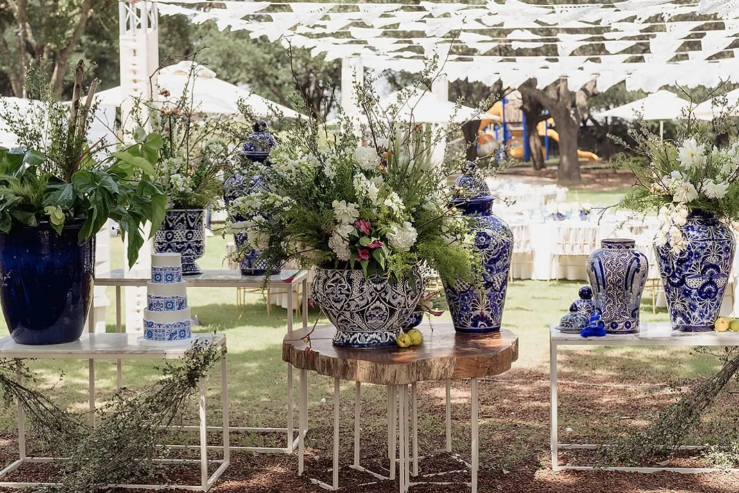 Tibores de talavera con arreglo floral sobre bases de madera y acero